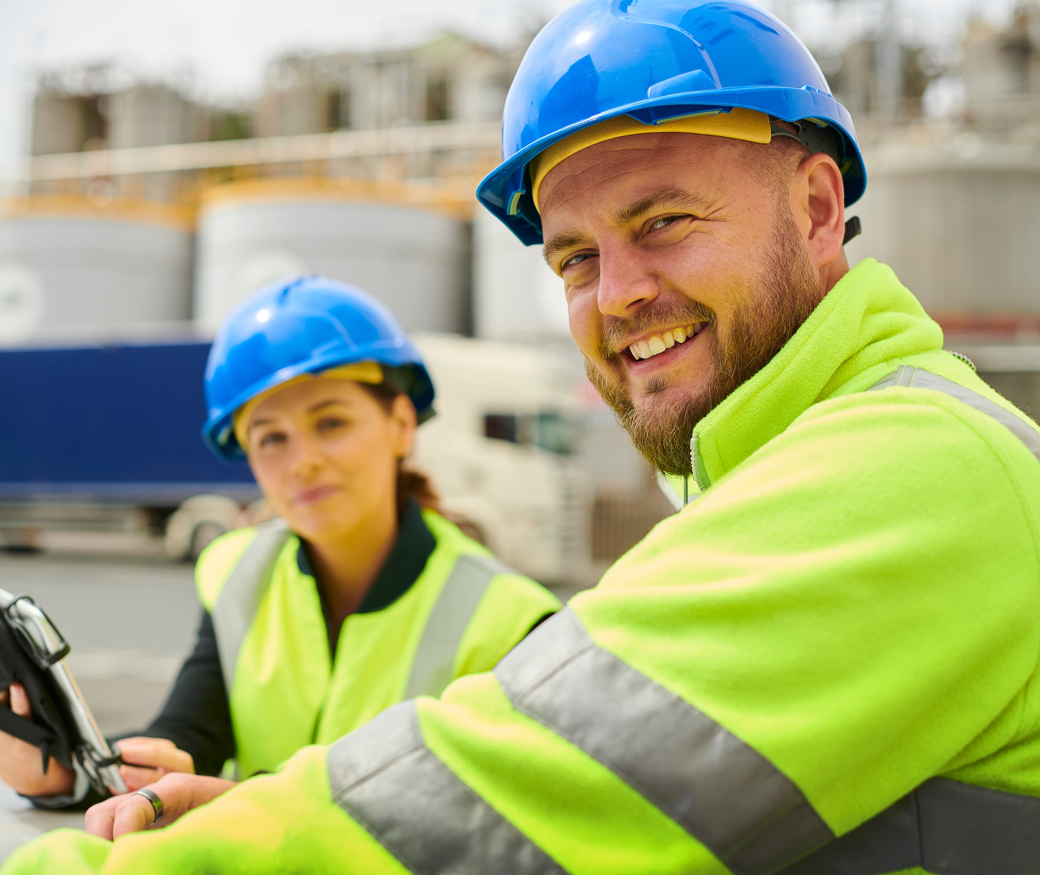 Female and male smiling wearing PPE on a construction site.